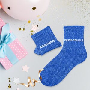 Une paire de chaussettes courtes en coton, parsemées de paillettes bleues scintillantes. L'inscription "Attachante" est brodée sur une chaussette et "Casse-couille" sur l'autre, en blanc.