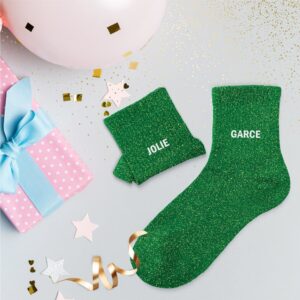 chaussettes dépareillées vertes à paillettes avec les mentions "Jolie" et "Garce" en blanc