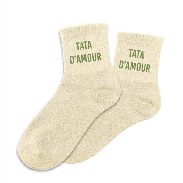 CHAUSSETTES PAILLETTES TATA D'AMOUR. A la recherche d'une paire de chaussettes originale qui tient votre tata au chaud ? Notre paire de chaussettes à paillettes "Tata d'Amour" est l'accessoire Mode & Beauté idéal ! Taille : 36-42 Ces chaussettes à paillettes couleur sable avec la mention "Tata d'Amour" sont la garantie de passer un hiver avec style bien au chaud.