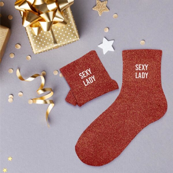 Envie d'ajouter une dose d'originalité, de fantaisie et de sensualité à vos tenues, tout en restant confortablement au chaud ? Notre paire de chaussettes à paillettes "Sexy Lady" est l'accessoire Mode idéal ! Avec leur couleur éclatante (rouge/rose gold à paillettes) et le message "SEXY LADY" discrètement mais fièrement affiché, elles sont parfaites pour celles qui aiment allier confort et audace. Que ce soit pour pimenter une tenue de soirée, ajouter une touche de fun à un look décontracté, ou simplement pour vous sentir fabulous à la maison, ces chaussettes sont un véritable coup de cœur !