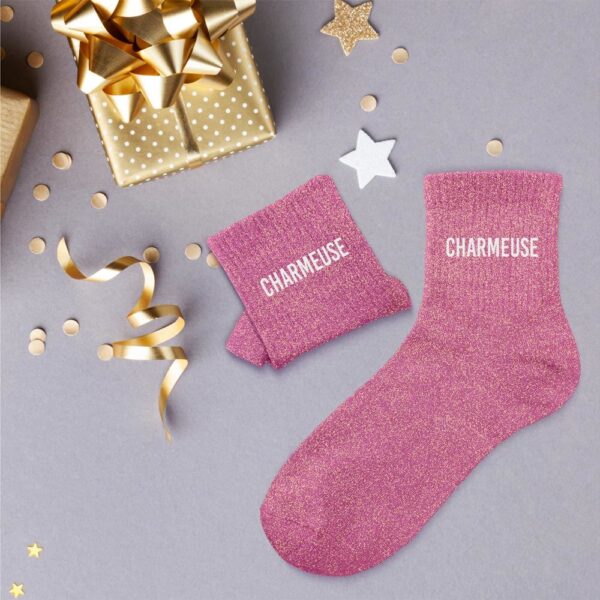 À la recherche d'une paire de chaussettes originale qui tient au chaud et exprime une personnalité pétillante et pleine de charme ? Notre paire de chaussettes à paillettes "Charmeuse" est l'accessoire Mode idéal ! Avec leur couleur rose vif scintillante et la mention "CHARMEUSE" inscrite en blanc, elles sont la garantie de passer un hiver bien au chaud tout en affichant un message audacieux et séduisant. Elles sont parfaites pour celles qui aiment attirer l'attention avec finesse et briller de mille feux.