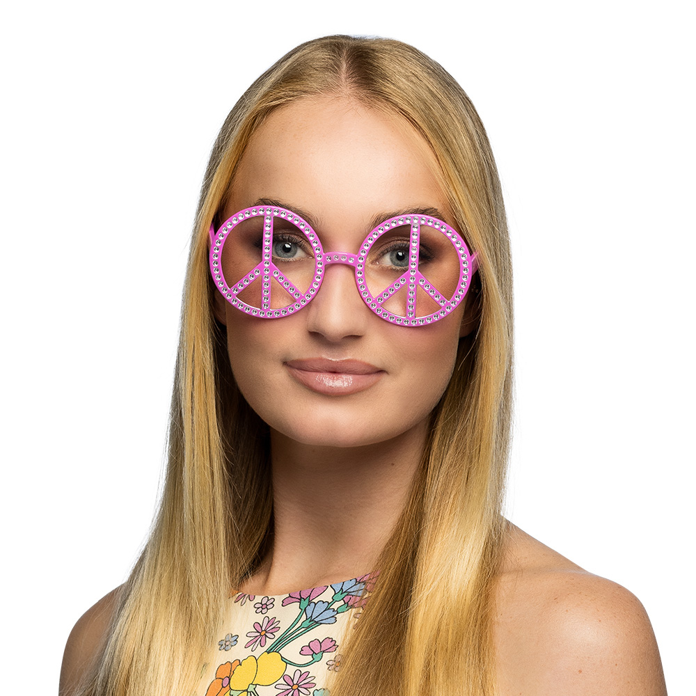 Une paire de lunettes de soleil de déguisement, avec une monture en plastique rose. Les verres sont transparents, mais un motif de symbole 'Peace and Love' est intégré à l'intérieur de chaque cercle de la monture. Le contour des symboles est décoré de petits strass blancs.