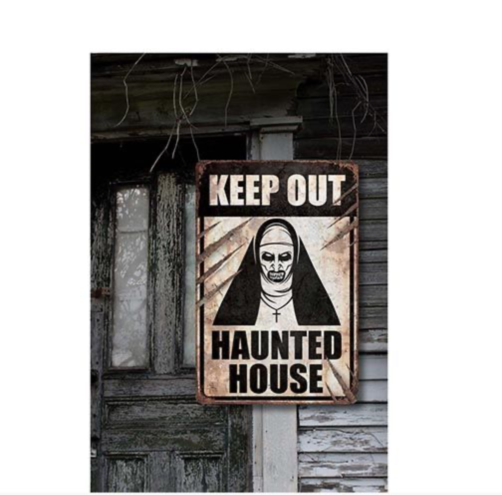 Pancarte décorative d'Halloween à l'aspect rouillé et vieilli. Elle présente l'image d'une nonne maléfique noire et blanche et le texte "KEEP OUT HAUNTED HOUSE"