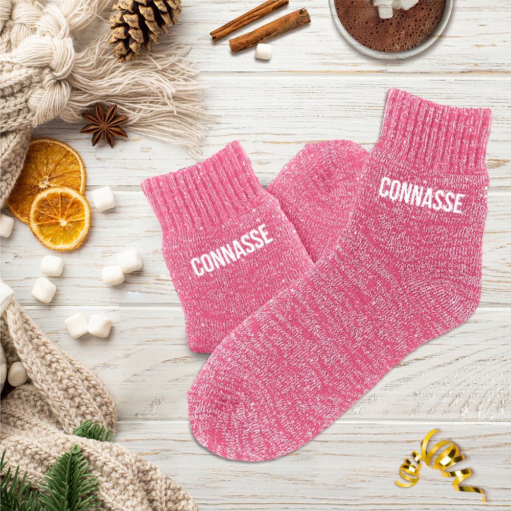 Paire de chaussettes polaires épaisses de couleur rose chiné pailleté, avec le mot "CONNASSE" imprimé en blanc sur les deux pieds.