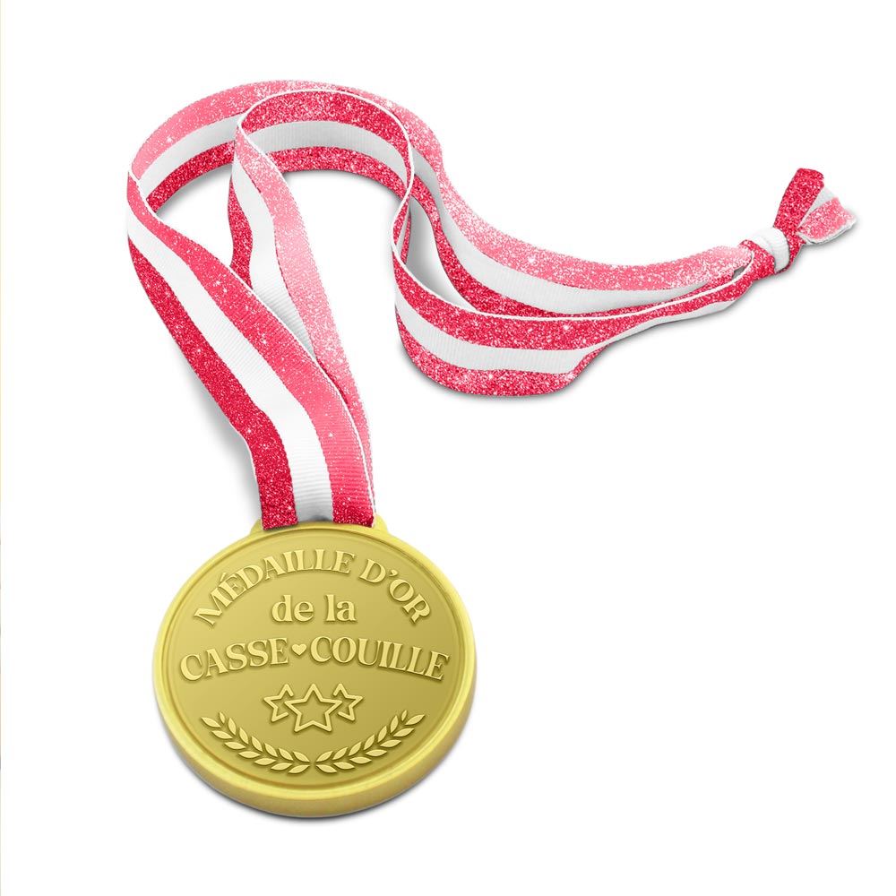 Médaille dorée avec inscription humoristique "Médaille d'or de la Casse-Couille", étoiles et lauriers, suspendue à un ruban rayé rose pailleté et blanc.