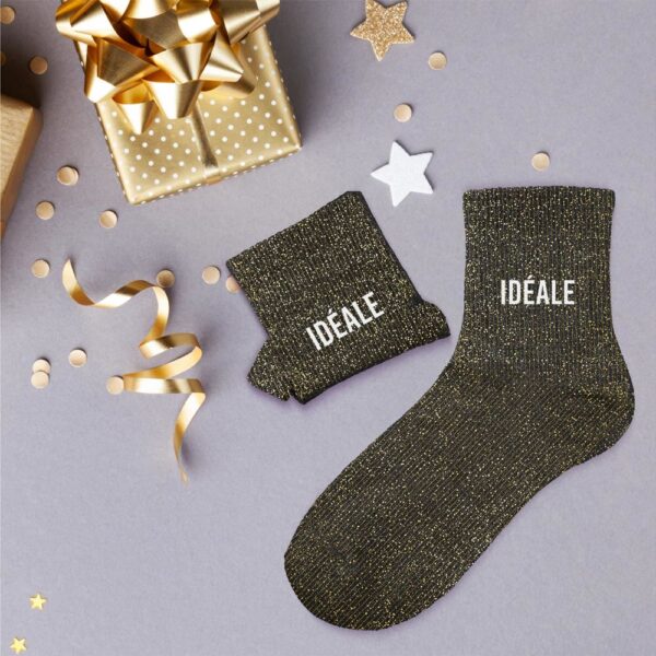 Paire de chaussettes noires scintillantes avec des paillettes dorées et l'inscription "IDÉALE" en lettres blanches