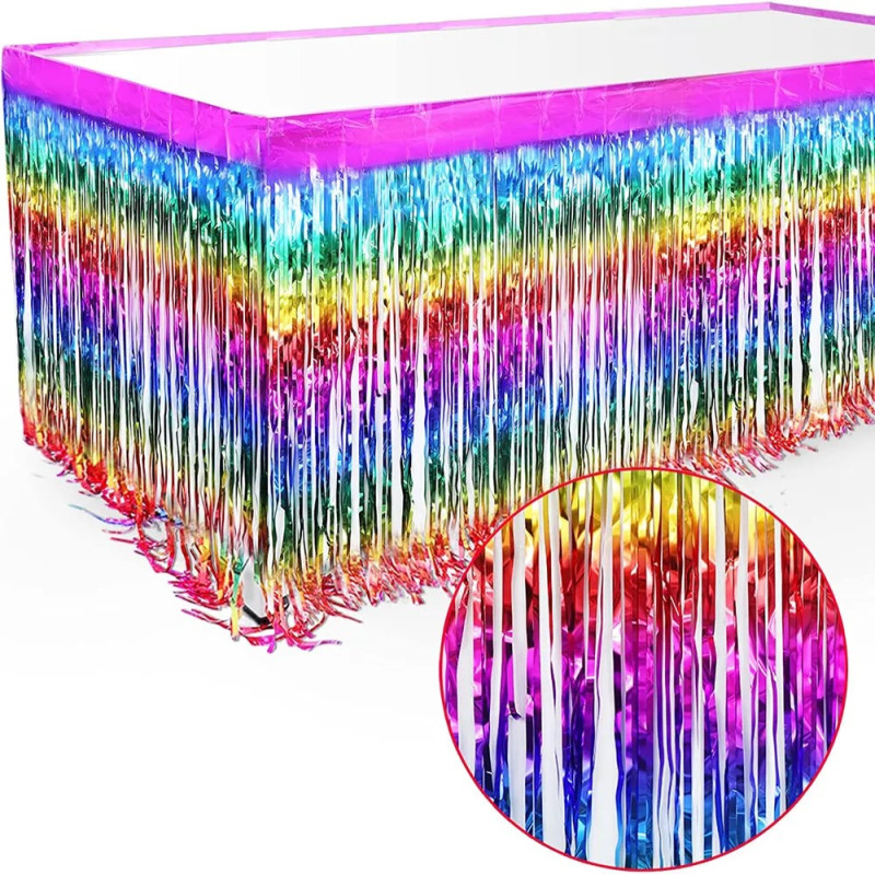 Jupe de table décorative à franges fines multicolores métallisées. Les franges présentent un dégradé de couleurs arc-en-ciel brillant (rose, jaune, vert, bleu, rouge). Le haut de la jupe possède une bordure rose fuchsia satinée.